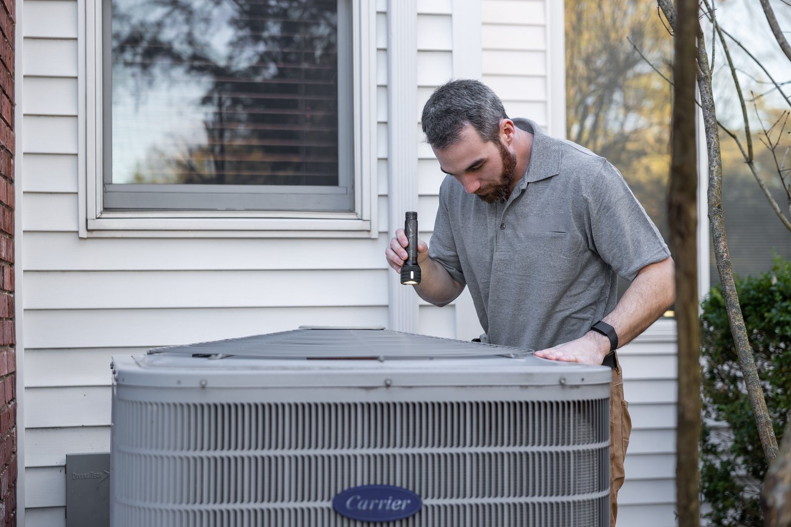 HVAC technician inspecting an outdoor air conditioning unit